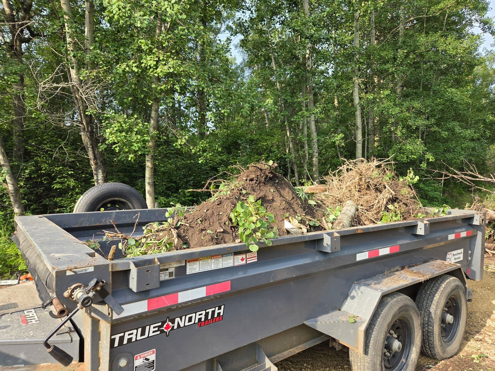 Dump trailer loaded with brush, roots and soil cleared from an acreage