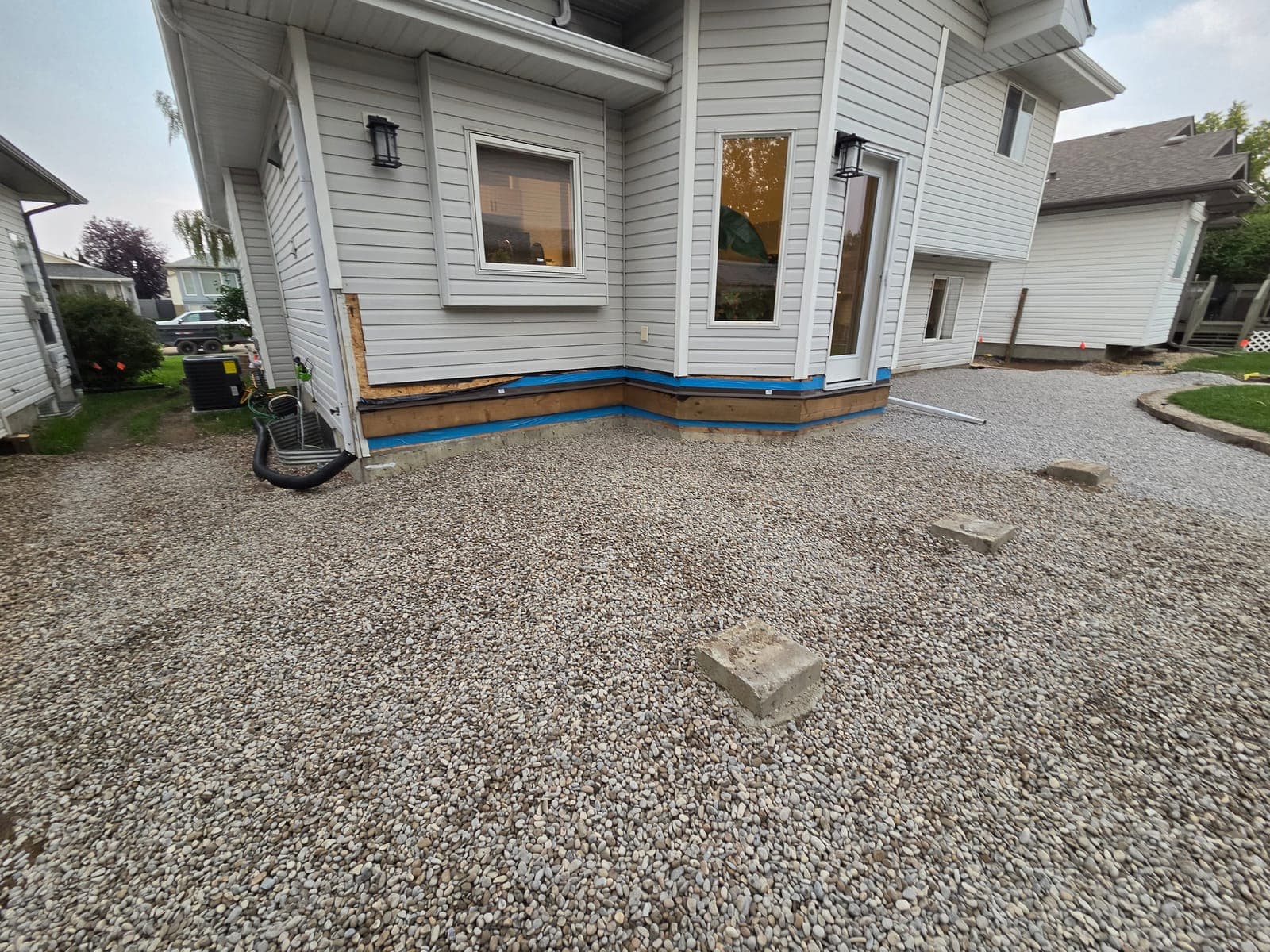 Clean washed rock laid around the rear foundation of a house in Spruce Grove