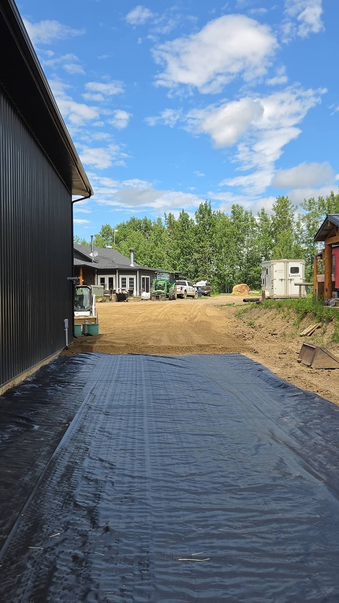 Geotextile fabric laid out along a shop wall before gravel is spread