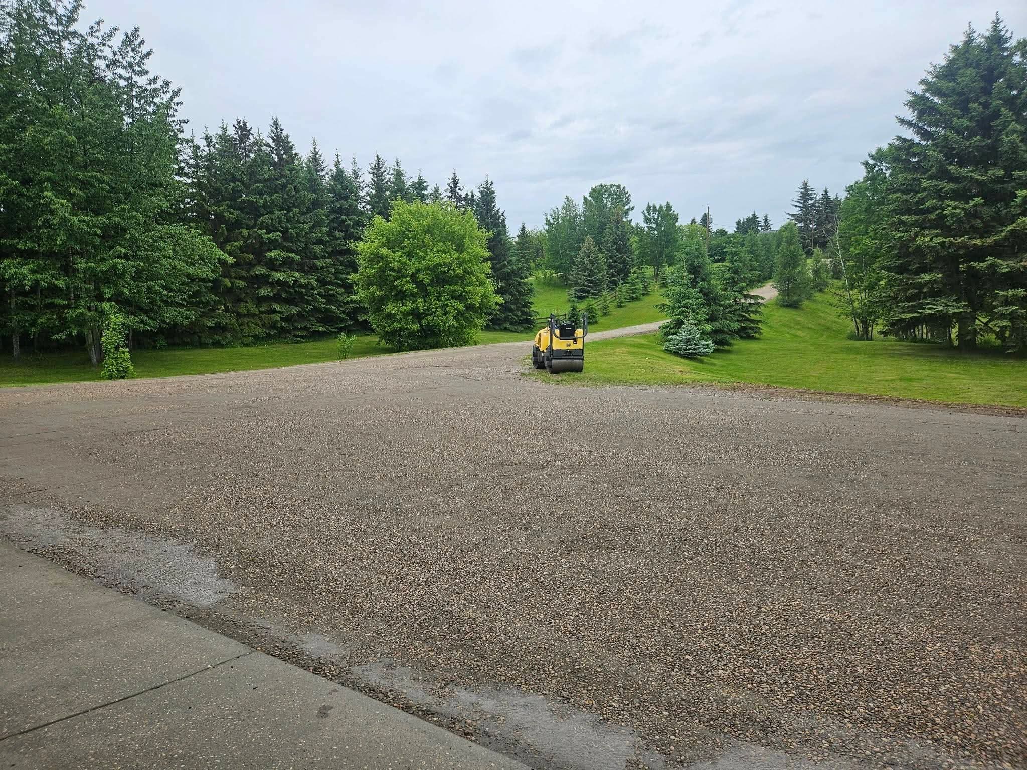 Large gravel parking area with a ride-on vibratory roller compacting it