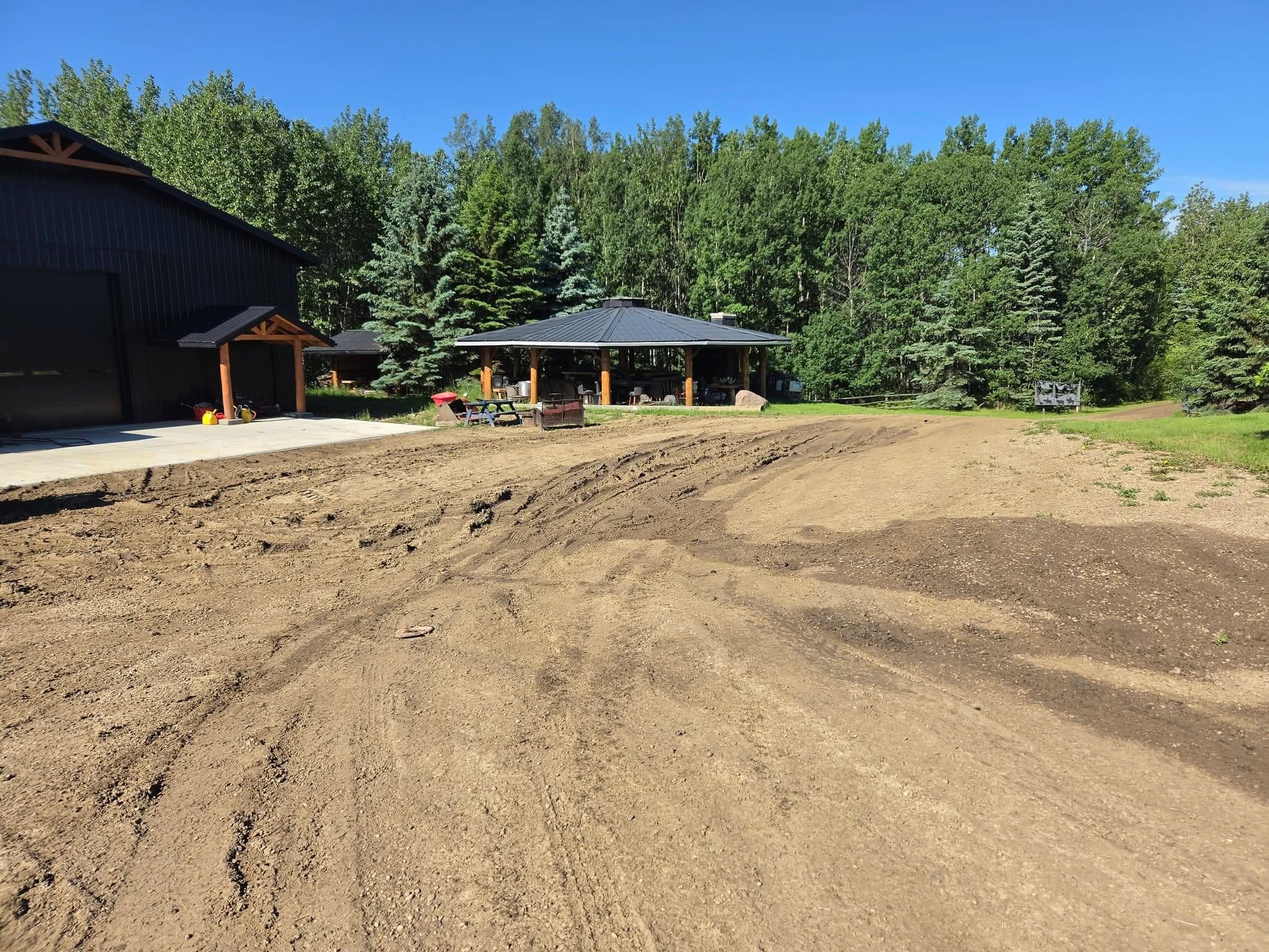 Bare, rutted dirt yard in front of a black shop building